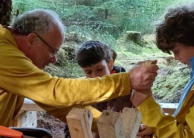 A man teaches woodwork to two boys